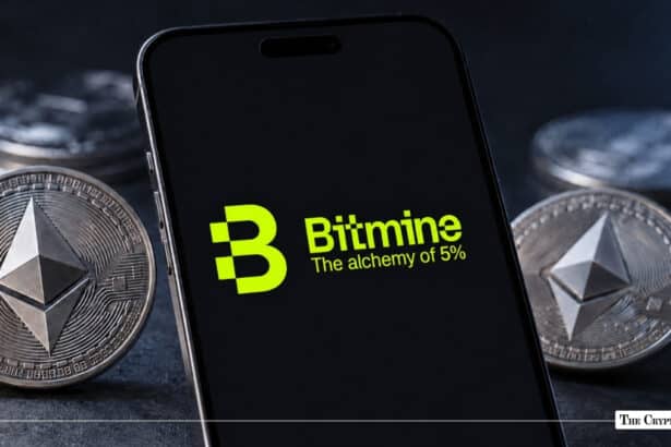 Black smartphone screen displaying the green Bitmine logo and slogan "The alchemy of 5%" surrounded by physical Ethereum coins