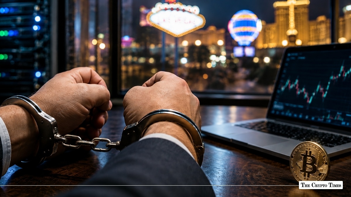 Handcuffed hands at a desk next to an open laptop showing trading charts, a gold Bitcoin coin, and the illuminated Las Vegas strip in the background