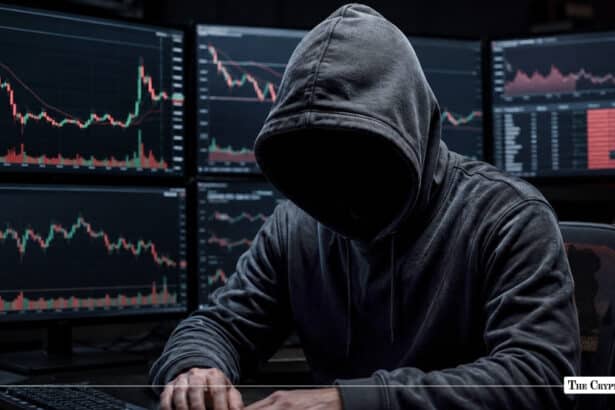 A hooded hacker sitting before multiple screens showing volatile red and green candlestick charts