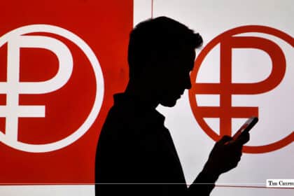 Silhouette of a person using a smartphone in front of large Digital Ruble symbol