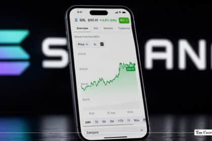 Smartphone displaying a Solana (SOL) price chart showing an upward green trend line, positioned in front of a blurred Solana logo