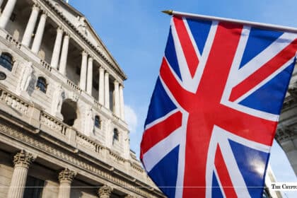 UK flag waving in front of the Bank of England building under a blue sky