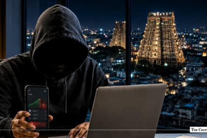 A hooded figure with a phone and laptop set against the illuminated temple skyline of Madurai, Tamil Nadu