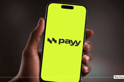 Smartphone displaying Payy app logo on a bright lime-green screen held in hand