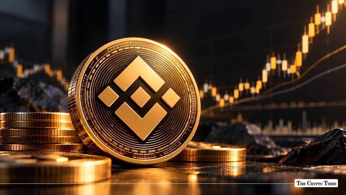 Physical Binance Coin (BNB) token displayed on a dark surface in front of a golden candlestick trading chart.