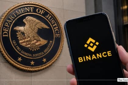 Smartphone displaying Binance app logo held in front of the U.S. Department of Justice wall seal