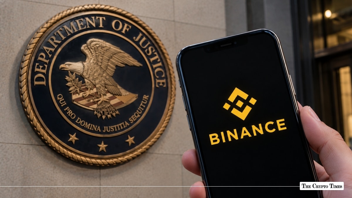 Smartphone displaying Binance app logo held in front of the U.S. Department of Justice wall seal