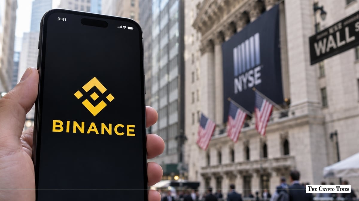 Hand holding a smartphone displaying the Binance app in front of the New York Stock Exchange
