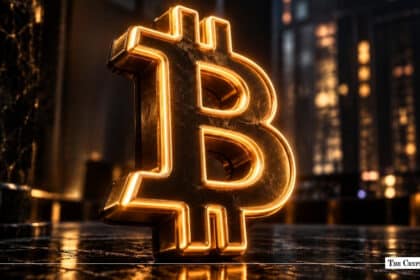 Glowing golden Bitcoin sign standing on a polished floor in front of illuminated city skyline lights at night