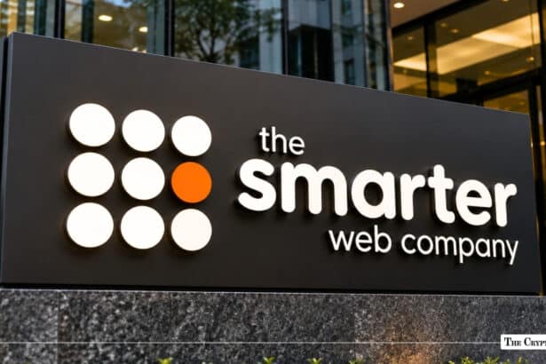 An outdoor signage board featuring the white and orange dot-grid logo and company name of "the smarter web company" mounted outside a modern office building.