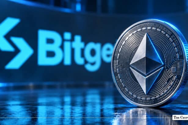 A physical silver Ethereum coin standing upright in front of a blue illuminated Bitget logo on a reflective dark surface.