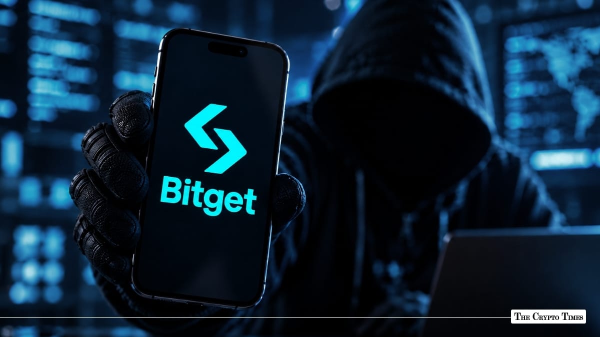 A gloved hand holding a smartphone displaying the Bitget logo in front of a hooded, shadowed figure.