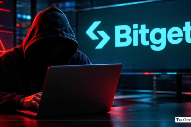 Hooded figure using a laptop next to a screen displaying the Bitget exchange logo.