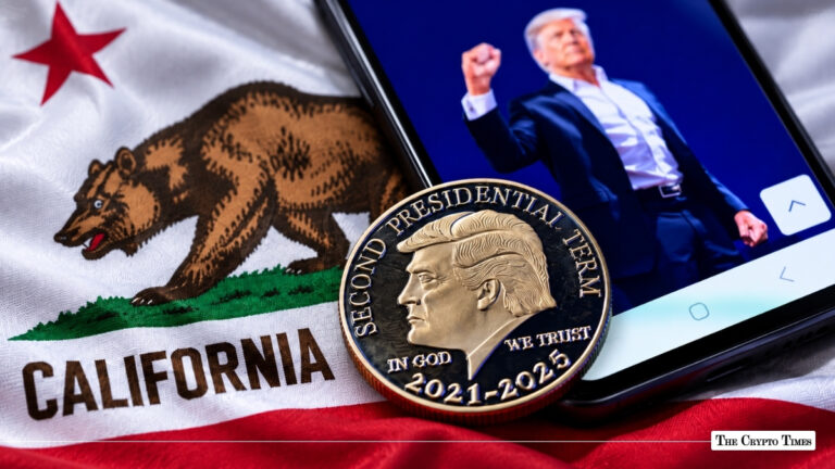A Donald Trump commemorative coin resting on the California state flag beside a smartphone displaying Trump's image.