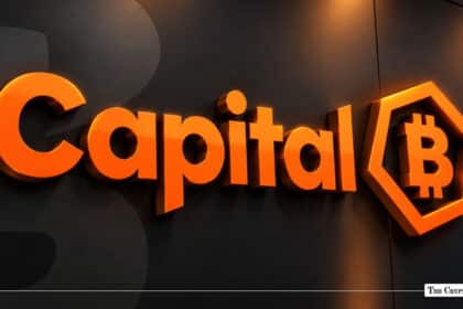 An illuminated 3D Capital B logo with a Bitcoin emblem mounted on a dark wall.