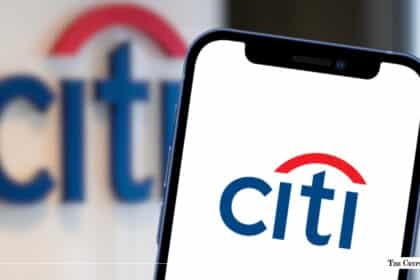 Smartphone displaying the Citi logo positioned in front of an out-of-focus Citi corporate sign