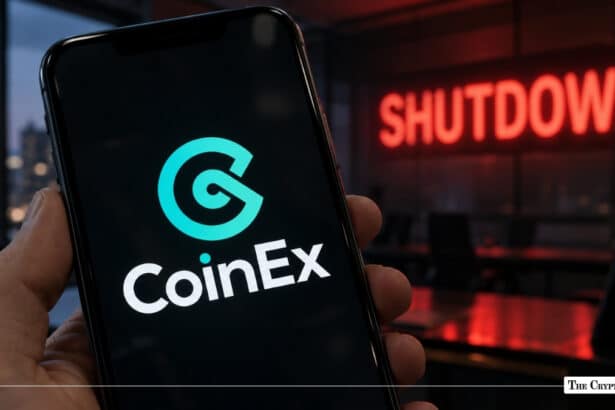 Hand holding smartphone displaying CoinEx crypto exchange app logo with glowing red SHUTDOWN sign in background