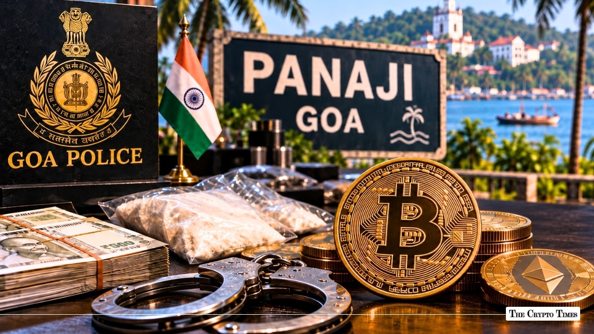 Physical crypto coins, Indian Rupee stacks, and handcuffs arranged in front of a Goa Police insignia and Panaji sign post.