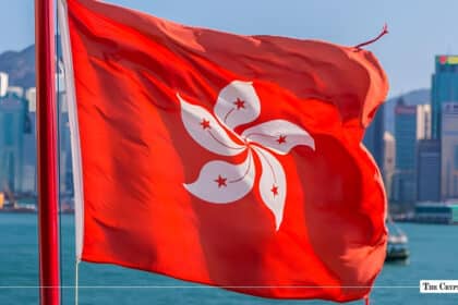 The flag of Hong Kong fluttering against the backdrop of the Victoria Harbour skyline.