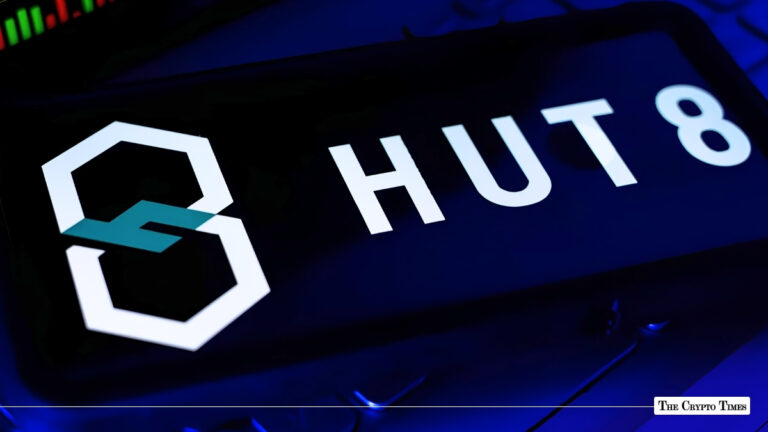 A smartphone displaying the Hut 8 logo on a screen angled over a laptop keyboard under blue lighting.