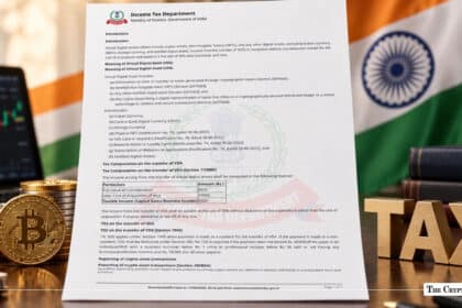 An Income Tax Department document detailing Virtual Digital Asset (VDA) rules, flanked by physical crypto coins, wooden "TAX" letters, and the Indian flag.