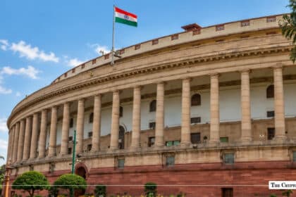 Indian Parliament building (Samvidhan Sadan) with the Indian national flag flying under a clear blue sky