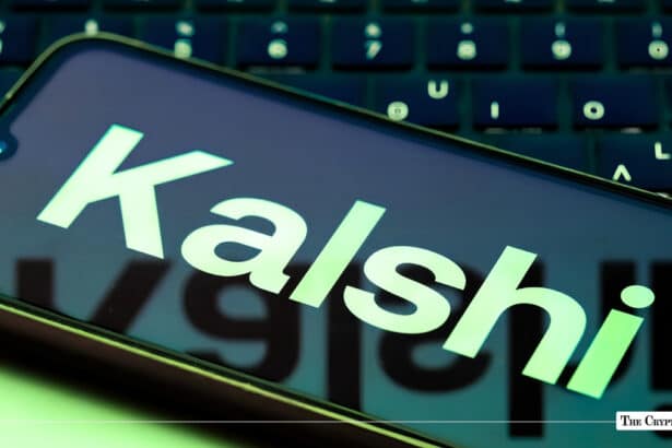 A smartphone displaying the light green Kalshi logo angled across a laptop keyboard.