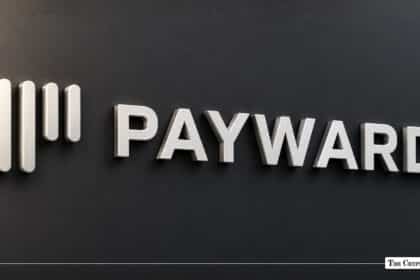 The silver Payward logo mounted on a dark wall.