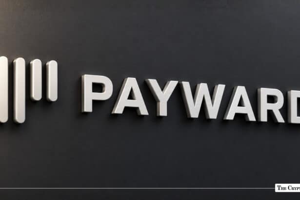 The silver Payward logo mounted on a dark wall.