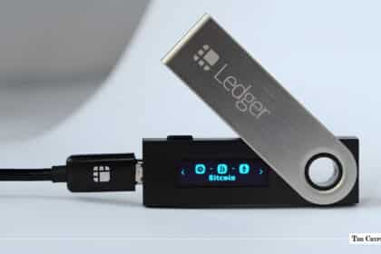 Black Ledger hardware wallet connected via USB displaying the Bitcoin icon on its digital screen