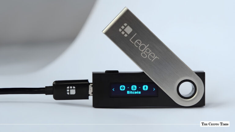 Black Ledger hardware wallet connected via USB displaying the Bitcoin icon on its digital screen