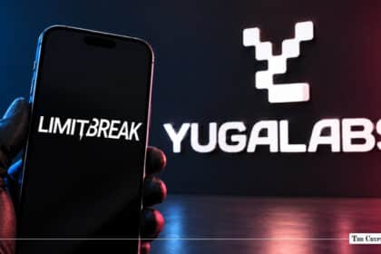 A gloved hand holding a smartphone displaying the Limit Break logo, with the Yuga Labs logo illuminated on the wall behind it.