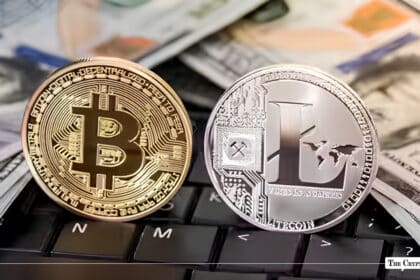 Gold Bitcoin and silver Litecoin coins resting on a laptop keyboard surrounded by US dollar bills.