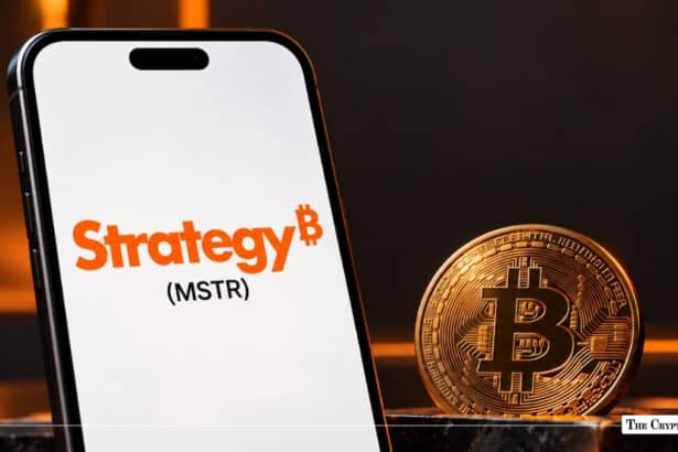 A smartphone displaying Strategy (MSTR) branding next to a gold Bitcoin coin.