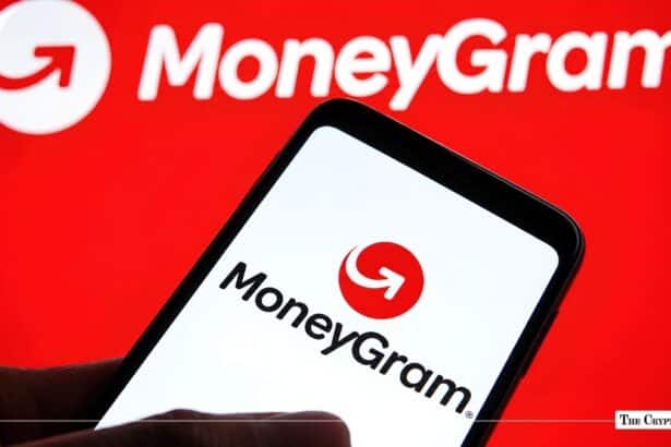 Hand holding a smartphone displaying the MoneyGram app logo against a red MoneyGram background.