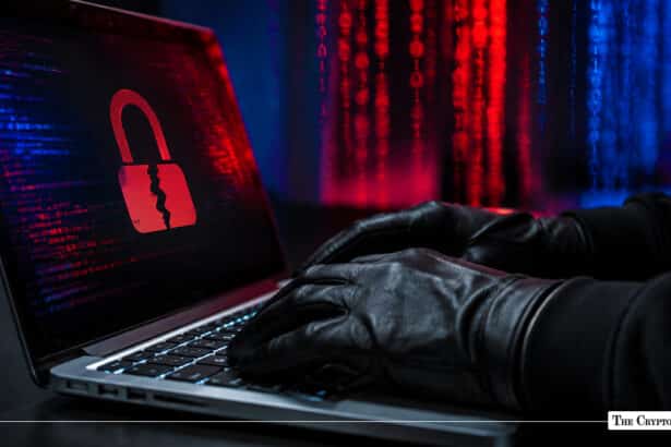 Gloved hands typing on a laptop displaying a cracked red padlock icon against a background of digital code matrix lines