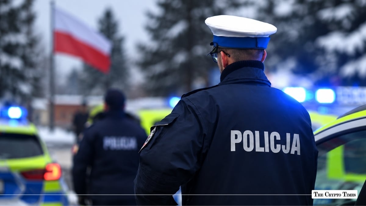 Polish police officer in uniform standing near police vehicles with the Polish flag in the background