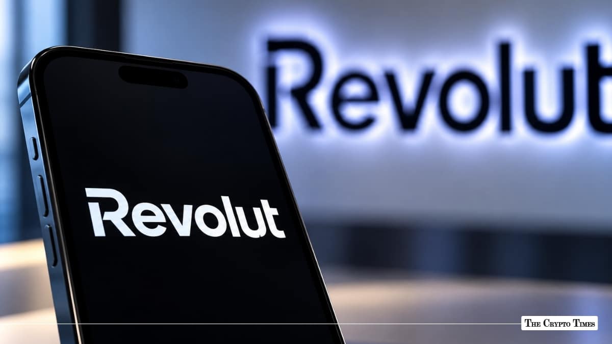 Smartphone displaying the Revolut app logo against a dark background with an illuminated Revolut wall sign behind it.