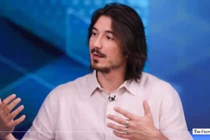 Robinhood CEO Tenev gesturing during an interview against a blue geometric background