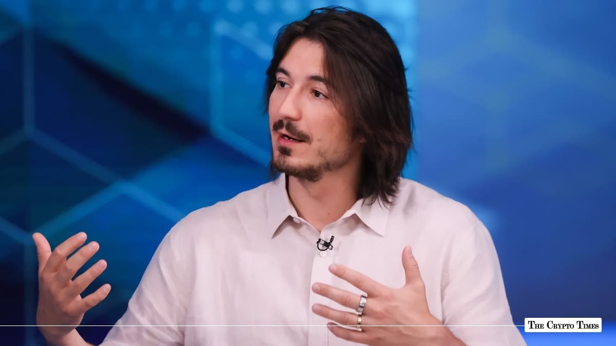 Robinhood CEO Tenev gesturing during an interview against a blue geometric background