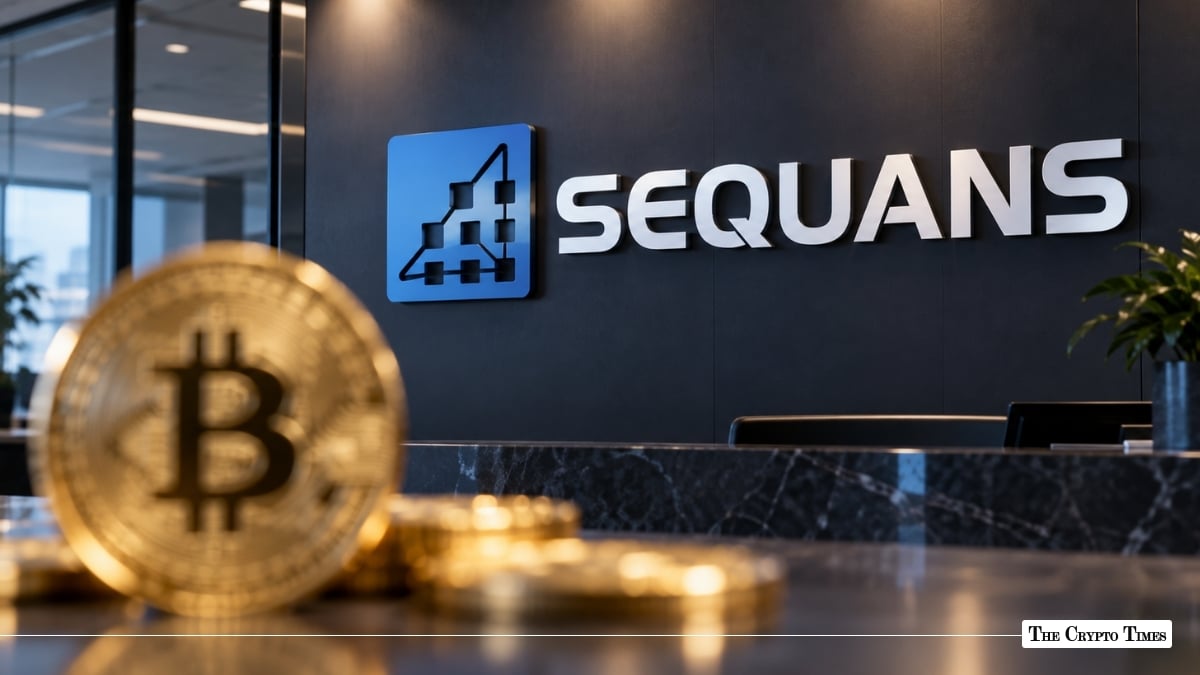 A physical gold Bitcoin coin in the foreground with the Sequans logo mounted on an office wall behind it.