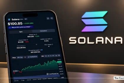 Smartphone displaying Solana price metrics in front of a backlit Solana logo display.