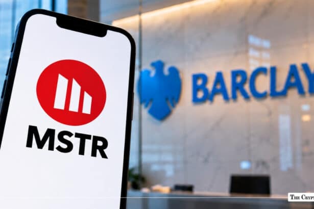 Smartphone displaying the MicroStrategy (MSTR) red circular logo with a blurred Barclays bank logo in the background