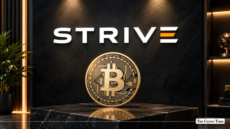Gold Bitcoin token displayed on a marble pedestal in front of a dark wall with the Strive company logo.