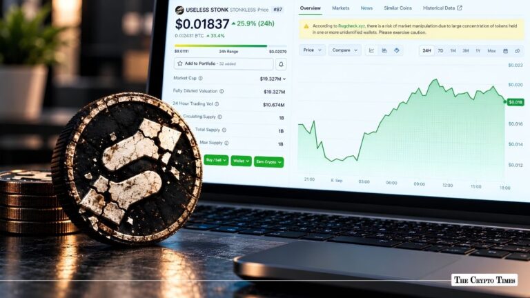 Physical USELESS STONK crypto token next to a laptop displaying the coin's price chart.