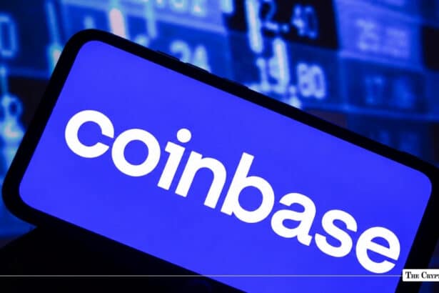 Smartphone displaying Coinbase app logo with financial stock market ticker screen in background