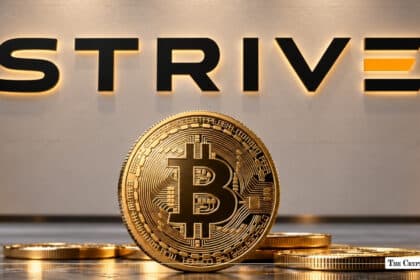 Physical Bitcoin coin in front of illuminated Strive corporate logo