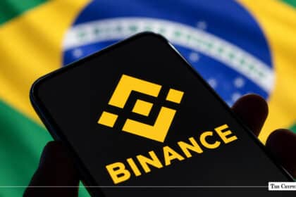 Smartphone displaying yellow Binance logo in hand with Brazilian flag in background