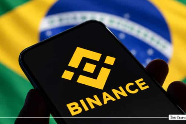 Smartphone displaying yellow Binance logo in hand with Brazilian flag in background