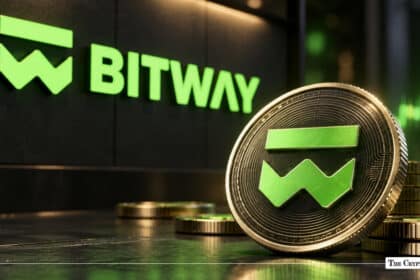 Physical Bitwave coin standing upright in front of a green illuminated Bitwave wall logo